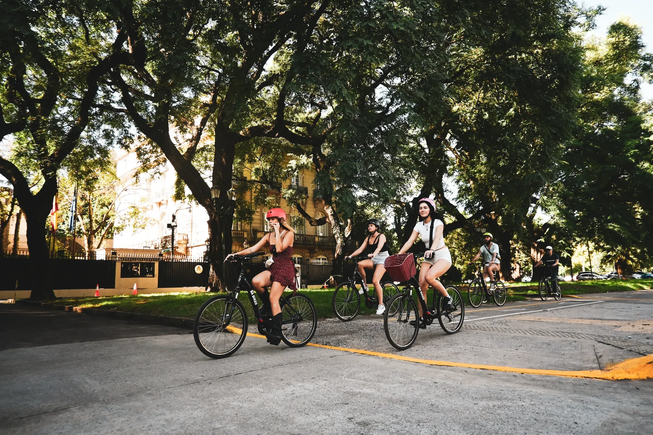 Cyclists riding beneath the trees in a Buenos Aires park.