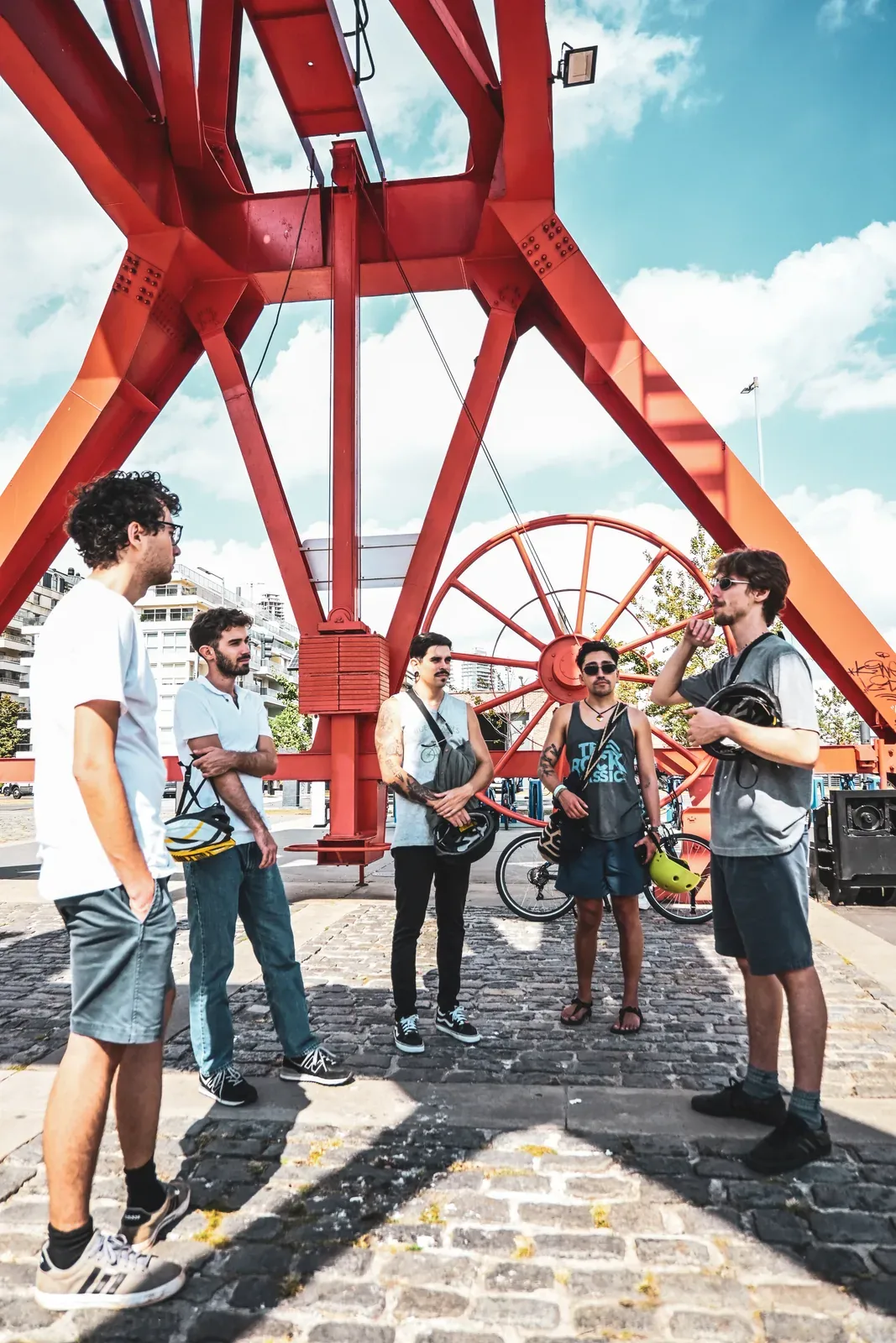 A bike-tour group gathered beneath a red steel bridge in Buenos Aires.