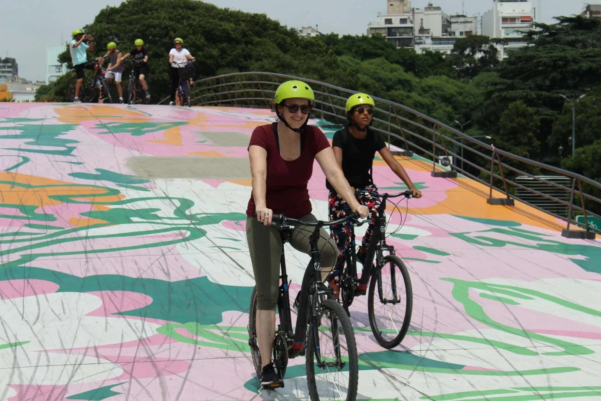 Two travelers riding bicycles together on a colorful city path.